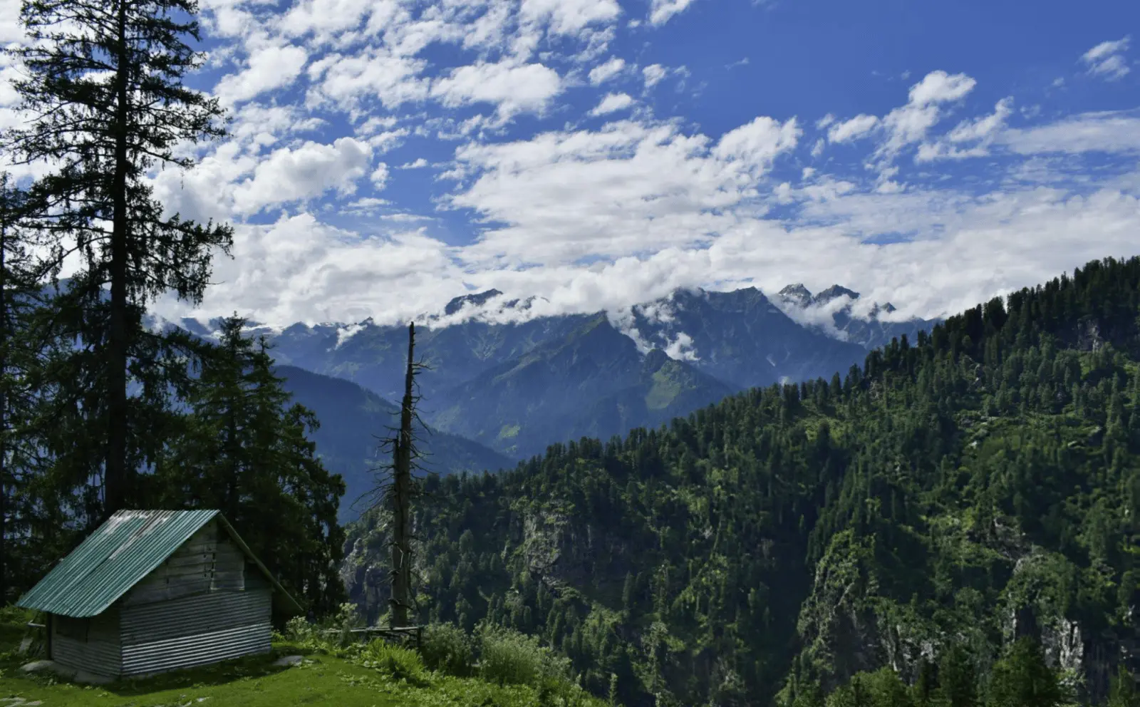 Trekking through Hampta Pass with panoramic views of snow-covered mountains.